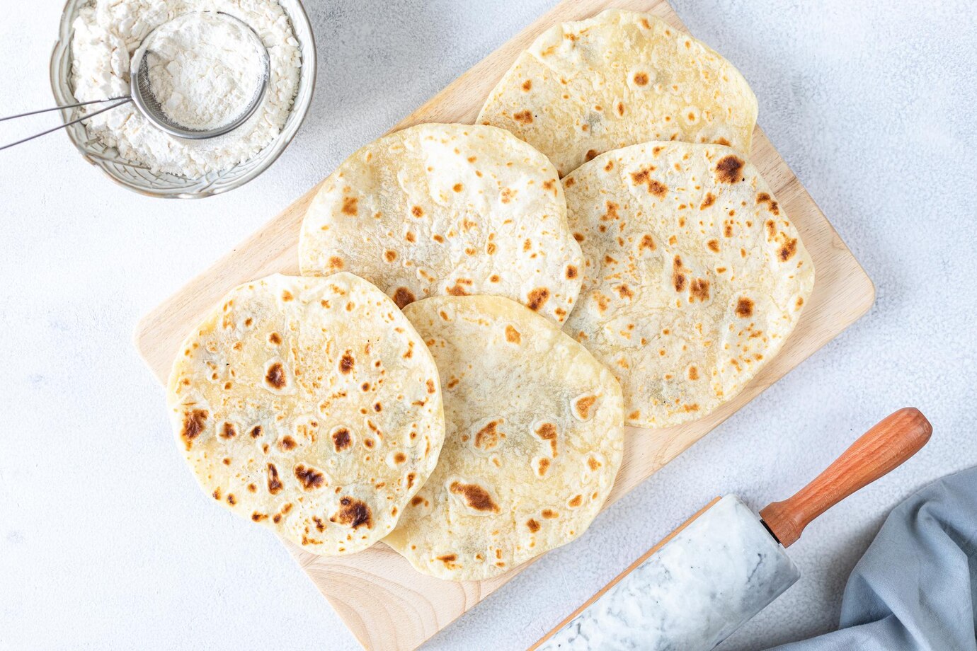 homemade-wheat-tortillas-pita-bread-tortilla-pita-with-ingredients-cooking-white-table-top-view_127032-2505